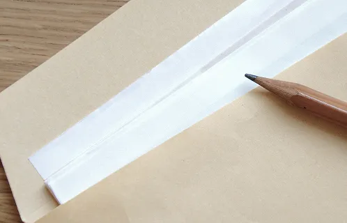 封筒に資料が入っており、その上に鉛筆が置いてある写真